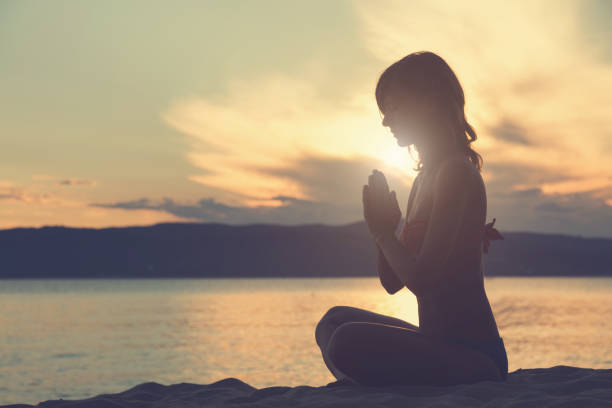 ツインレイサイレント期間湖畔で夕日を浴びながら祈る女性