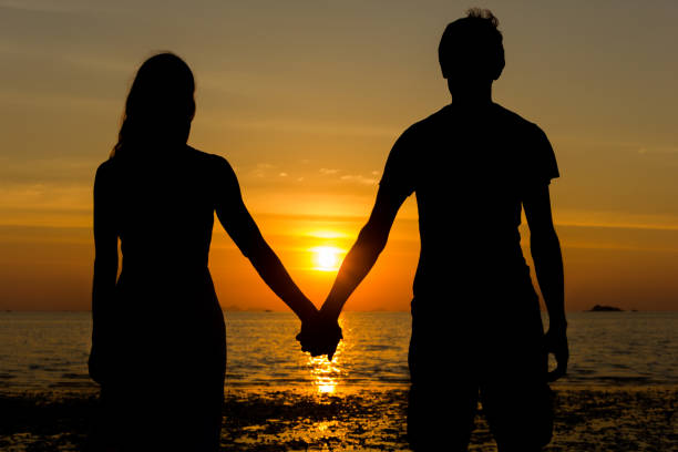ツインレイ男性特徴夕日の海辺で手をつなぐカップル