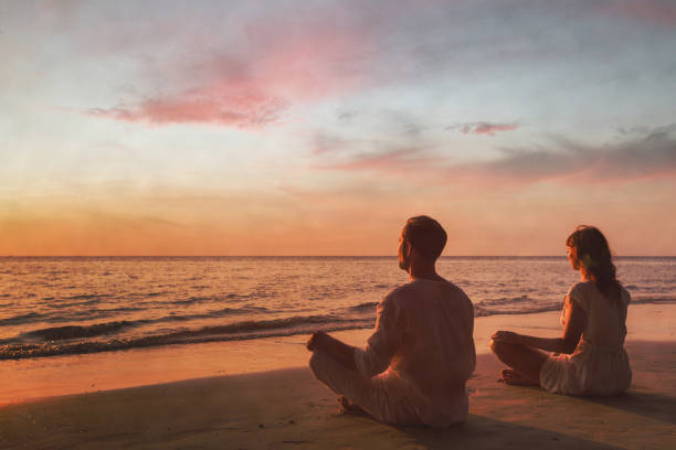 ツインレイ男性特徴夕日の海辺で瞑想するカップル