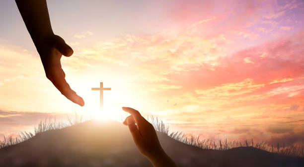 夕日と十字架の前で手を繋ごうとする男女