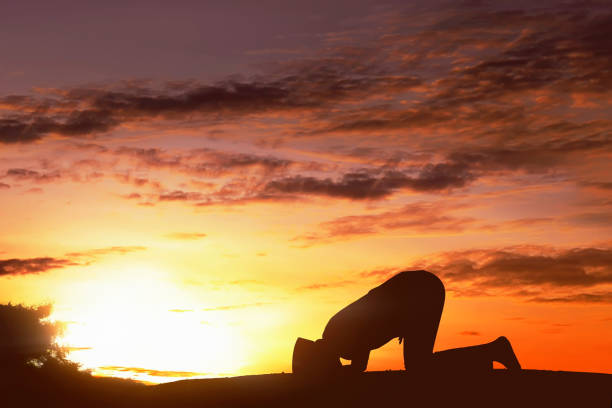 夕日と地に頭を付けて祈る男性