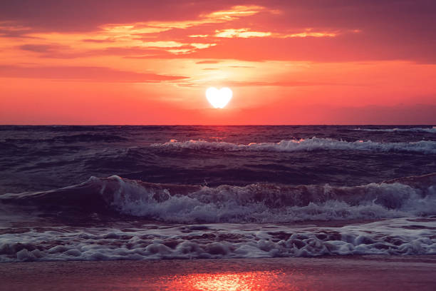 ハート型の夕日と波打つ海辺