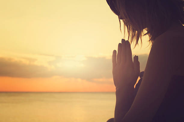 夕日に祈る女性